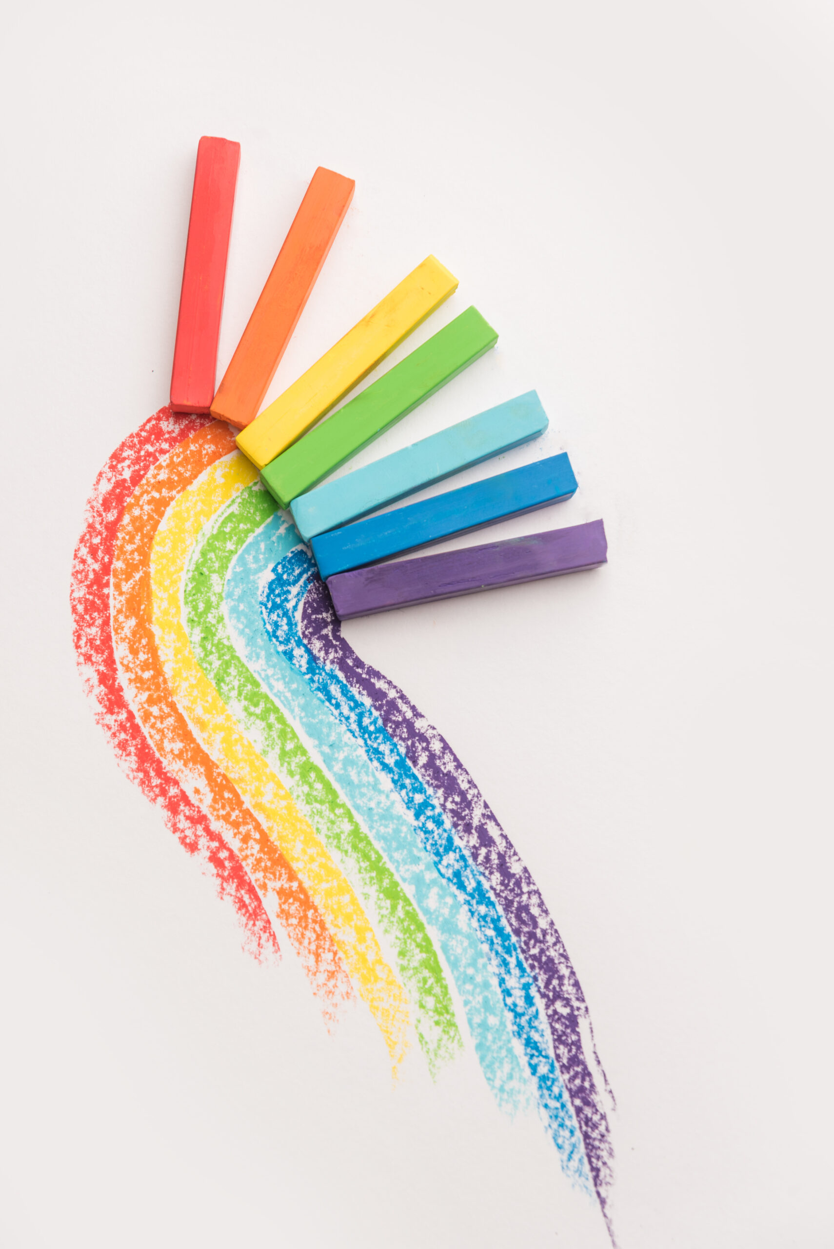 Rainbow gradient made of pastel crayon chalks over the colorful traces isolated over the white background